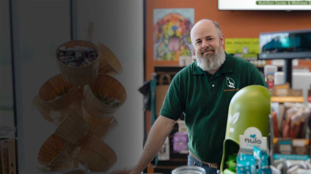Photo of a franchisee in a green shirt at the counter of an EarthWise Pet Store